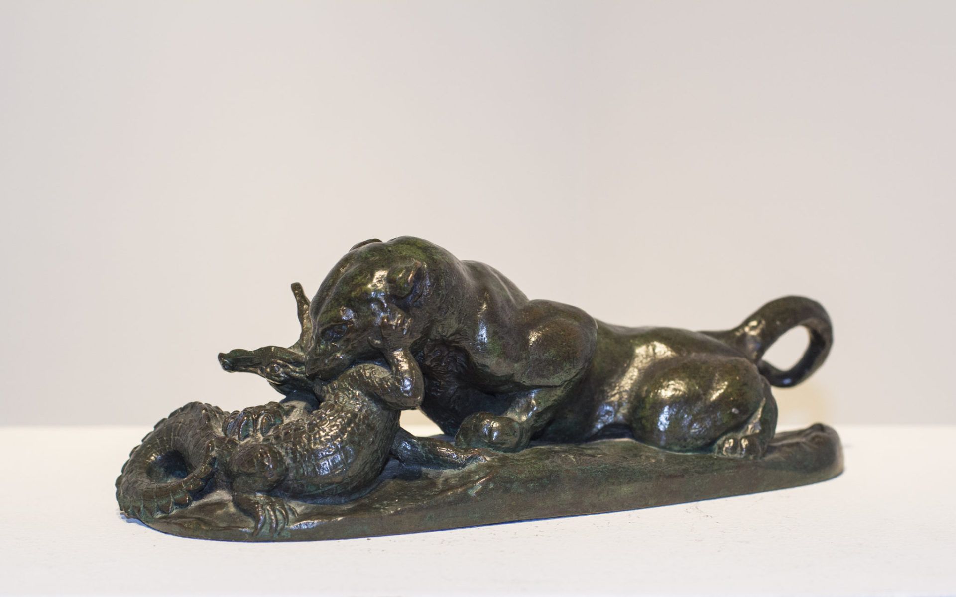 Alt text: Bronze sculpture of a jaguar with a crocodile's neck in its mouth