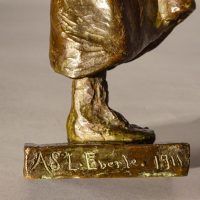 Alt text: Detail of bronze sculpture with signature reading 