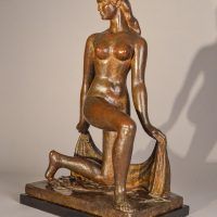 Alt text: Bronze sculpture of a nude dancer kneeling with one leg on the ground, holding a shawl behind her, angled view