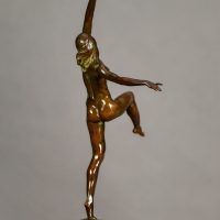 Alt text: Bronze sculpture of a nude woman posing with arms outstretched in an L shape and right leg lifted with knee bent