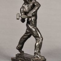 Alt text: Bronze sculpture of a muscular shirtless man swinging a hammer
