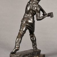 Alt text: Bronze sculpture of a muscular shirtless man swinging a hammer
