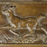 Alt text: Bronze relief of a trotting deer