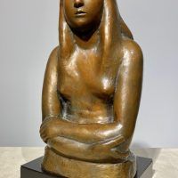 Alt text: Bronze sculpture of a girl with crossed arms, angled view