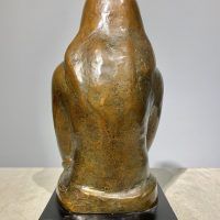 Alt text: Bronze sculpture of a girl with crossed arms, rear view