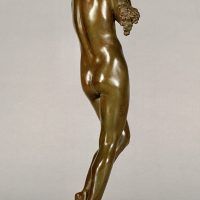Alt text: Bronze sculpture of a nude woman standing and cradling grapes over her shoulder and into her chest, angled view
