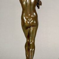 Alt text: Bronze sculpture of a nude woman standing and cradling grapes over her shoulder and into her chest, rear view