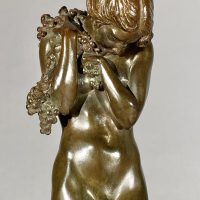 Alt text: Bronze sculpture of a nude woman standing and cradling grapes over her shoulder and into her chest, frontal detail view