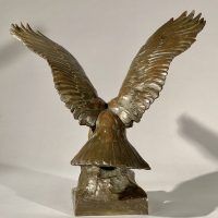 Alt text: Bronze sculpture of eagle preparing to take flight off a rocky point, rear view 