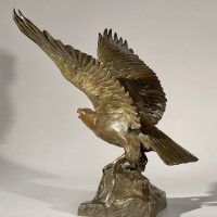 Alt text: Bronze sculpture of eagle preparing to take flight off a rocky point, side view 