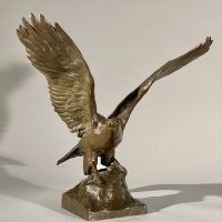 Alt text: Bronze sculpture of eagle preparing to take flight off a rocky point, angled view 