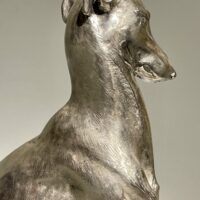 Alt text: Silvered bronze sculpture of a seated dog
