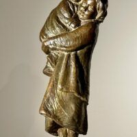 Alt text: Bronze sculpture of a young woman carrying her baby in 1910s clothing
