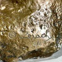 Alt text: Bronze sculpture of a frog, signature detail