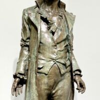 Alt text: Bronze sculpture of a standing man, detail