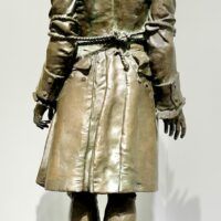 Alt text: Bronze sculpture of a standing man, rear view