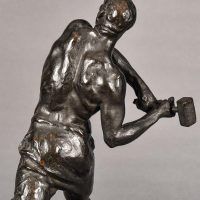 Alt text: Bronze sculpture of a muscular shirtless man swinging a hammer, detail