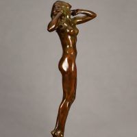 Alt text: Bronze sculpture of a nude woman standing with elbows out and hands framing her face