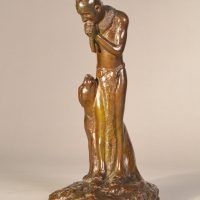 Alt text: Bronze sculpture of a Native American man playing flute, looking down at a Puma sitting beside him, side view