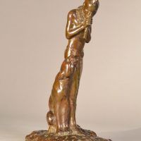 Alt text: Bronze sculpture of a Native American man playing flute, looking down at a Puma sitting beside him, angled view