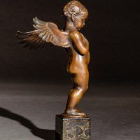 Alt text: Small bronze cherub sculpture with outstretched wings, side view