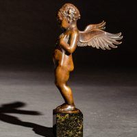 Alt text: Small bronze cherub sculpture with outstretched wings, side view