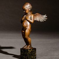 Alt text: Small bronze cherub sculpture with outstretched wings, angled view