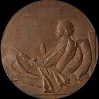 Alt text: Bronze bas relief of Robert Louis Stevenson writing in bed
