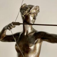 Alt text: Bronze sculpture of a woman holding a bow and arrow, detail