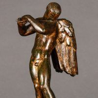 Alt text: Bronze sculpture of an angel playing flute, detail
