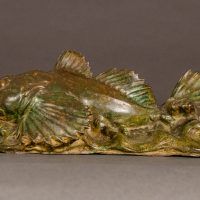 Alt text: Bronze sculpture of a sculpin fish atop the water, side view