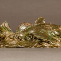Alt text: Bronze sculpture of a sculpin fish atop the water, angled view