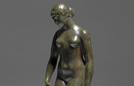 Alt text: Smooth bronze sculpture of a standing nude woman holding draped fabric