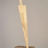 Alt text: Welded steel sculpture jutting out from a single point in an incised concrete block, angled view