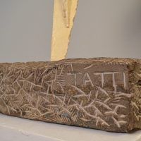 Alt text: Detail of steel sculpture with artist signature incised in concrete: 
