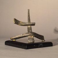 Alt text: Abstract soldered lead sculpture atop a wooden base with six points, angled view