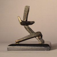 Alt text: Abstract soldered lead sculpture atop a wooden base with six points, side view