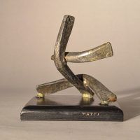 Alt text: Abstract soldered lead sculpture atop a wooden base with six points, side view