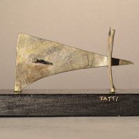 Alt text: Abstract soldered lead sculpture atop a wooden base, side view