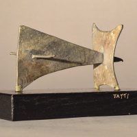 Alt text: Abstract soldered lead sculpture atop a wooden base, angled view