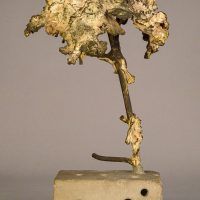 Alt text: Welded bronze sculpture shaped like a tree mounted on a slag block, side view