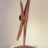 Alt text: Welded pickaxe sculpture resembling a propeller, angled view