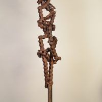 Alt text: Welded chain link sculpture with biomorphic figure, angled view
