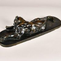 Alt text: Bronze sculpture of a lounging puma grooming itself