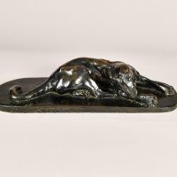 Alt text: Bronze sculpture of a lounging puma grooming itself