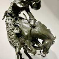Alt text: Bronze sculpture of a cowboy atop a scared horse startled by a rattlesnake