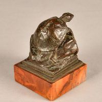 Alt text: Small bronze sculpture of a turtle atop a rock