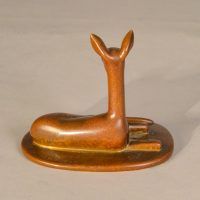 Alt text: Bronze sculpture of a doe lying down with her head and ears up, rear view