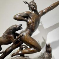 Detail of bronze sculpture of man running with dogs
