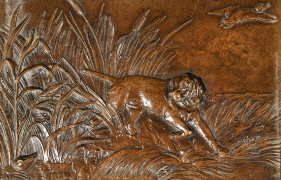 Alt text: Bronze relief of a hunting dog in reeds